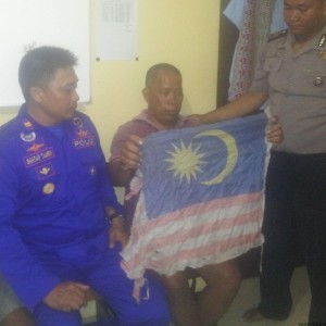 tersangka dengan membawa bendera malaysia saat diamankan petugas kepolisian (hfa)